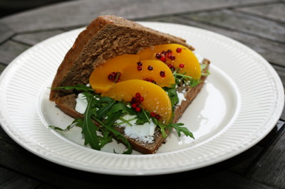 Broodje geitenkaas met perzik, roze peper en rucola